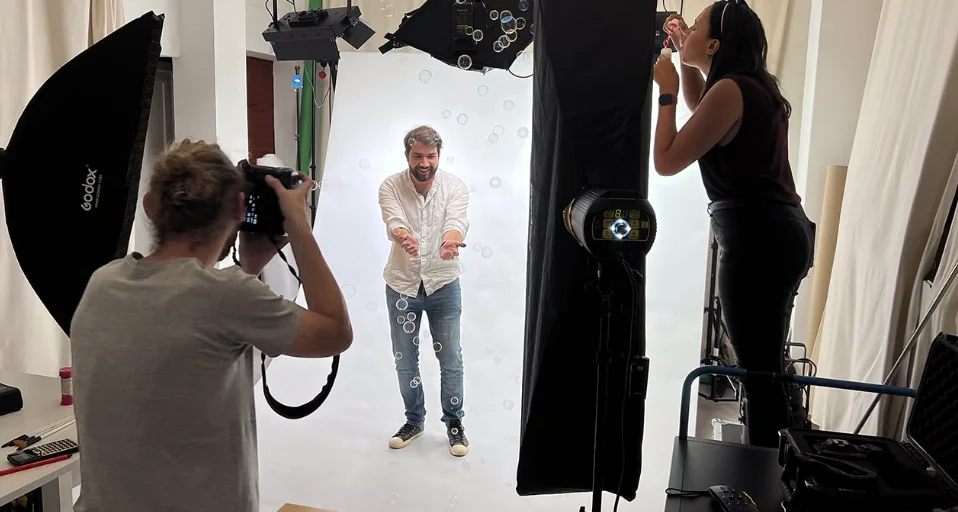 Séance de portrait en studio : photographe, éclairages et sujet sur fond clair.