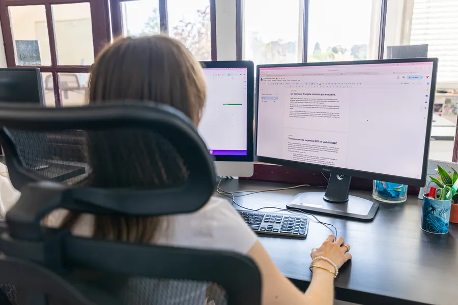 Une membre de l’équipe Zetruc, de dos, devant deux écrans ouverts sur un document de travail.
