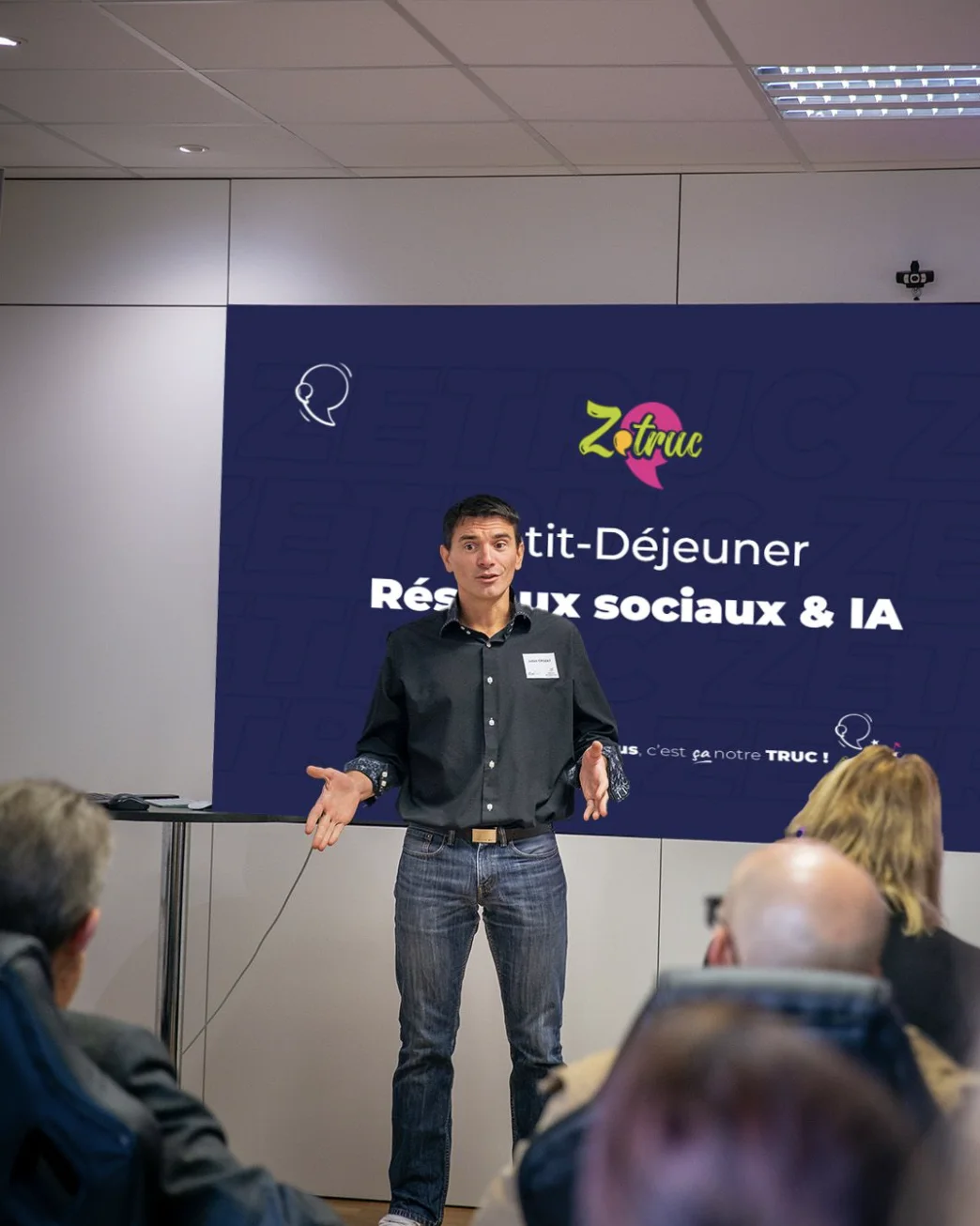 Julien Crozat anime un petit-déjeuner « Réseaux sociaux & IA » devant un écran Zetruc, face au public.