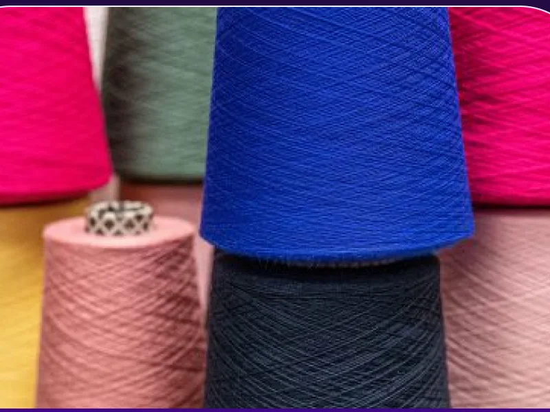 Des cônes de fil colorés, la matière première de l’atelier textile.