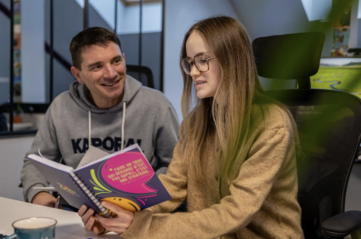 Deux membres de l'équipe consultant un livre de marque dans les bureaux de l'agence.